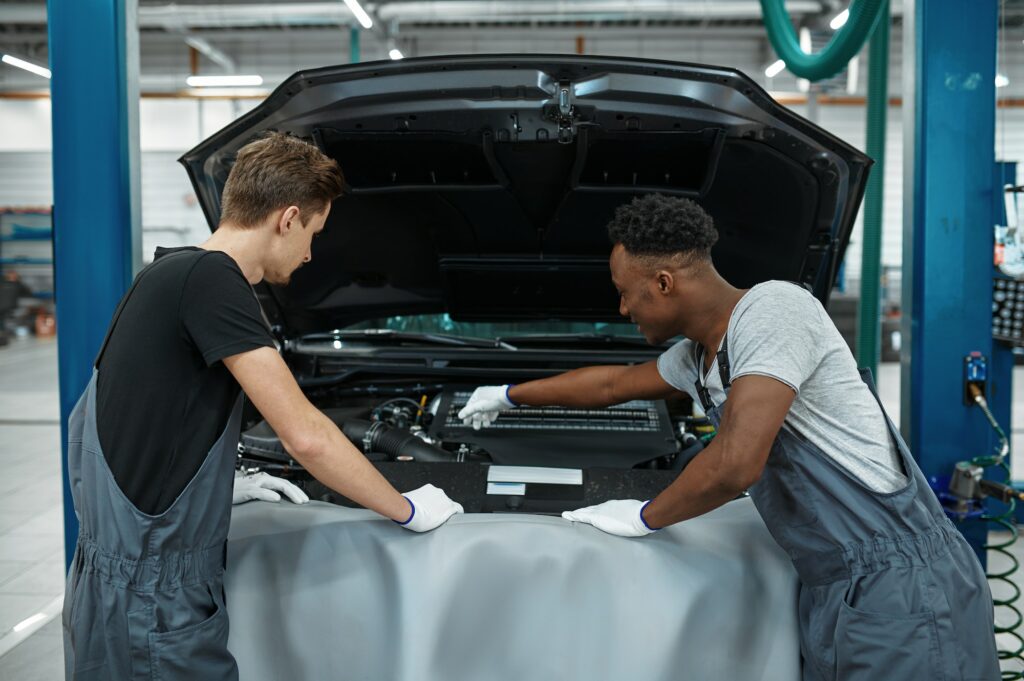 Two male mechanics checking motor, car service