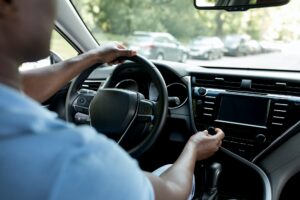 Unrecognizable black man driver turning on radio in auto